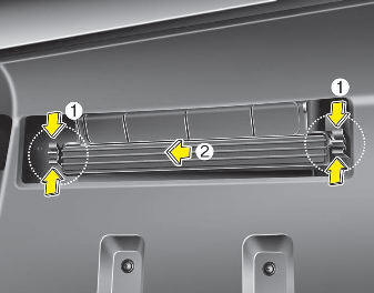 2. Remove the climate control air filter cover (2) while pressing the lock (1)